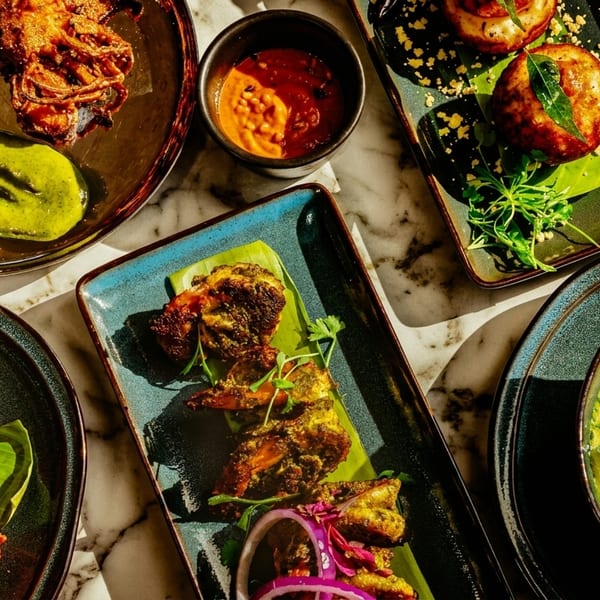 Overhead view of various Indian dishes, including fried seafood, curries, and sauces, on a marble table.